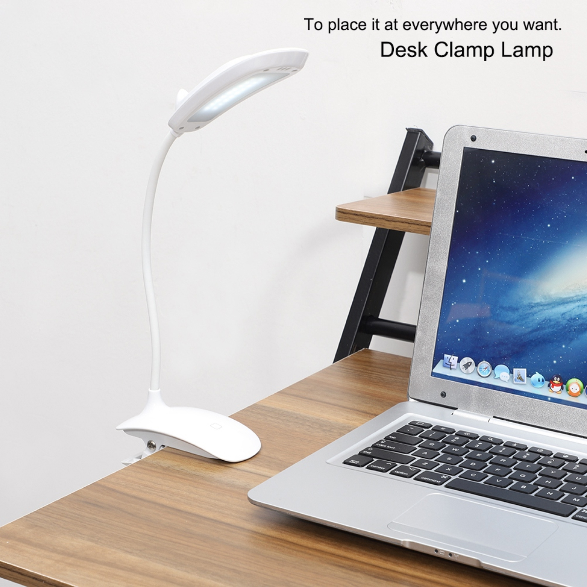 Eine weiße Schreibtischlampe ist an einem braunen Schreibtisch befestigt, neben einem Laptop. Im Hintergrund befinden sich ein Regal und eine weiße Wand.