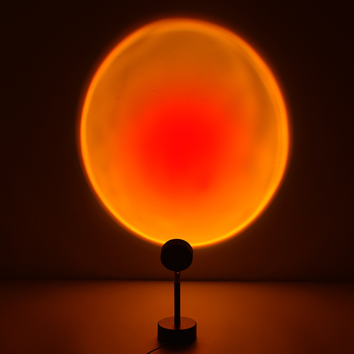 Eine Sonnenuntergangslampe projiziert einen orangefarbenen Kreis an die Wand. Die Lampe ist schwarz, hat einen runden Kopf und einen Ständer.