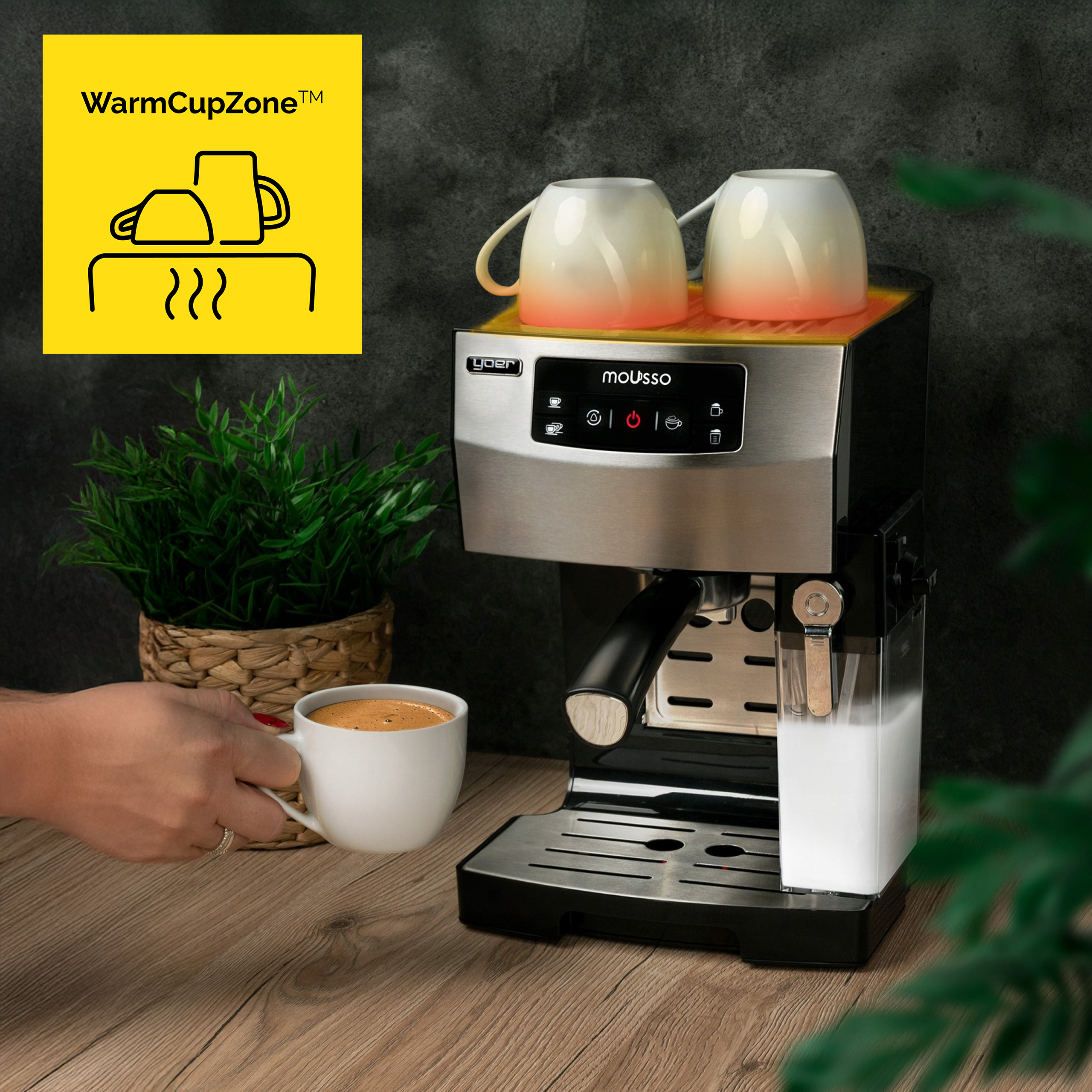 Ekspres do kawy z dwoma filiżankami na górze. Ręka trzyma filiżankę kawy. Żółty znak z WarmCupZone.
