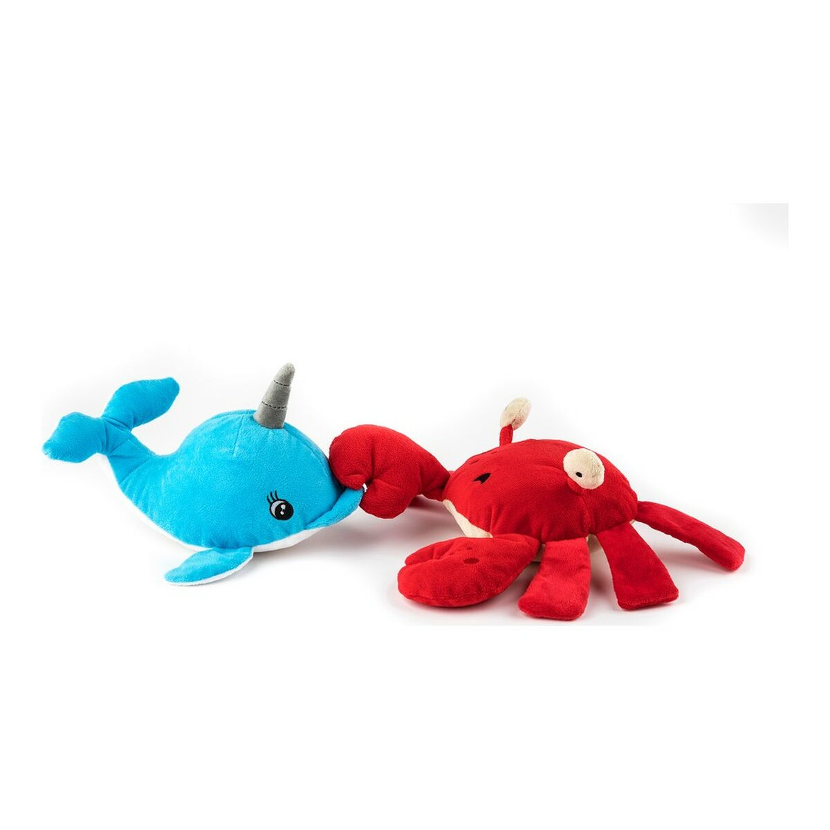 Un peluche di narvalo blu tocca un peluche di granchio rosso. Entrambi sono su sfondo bianco. I giocattoli sono morbidi e peluche.