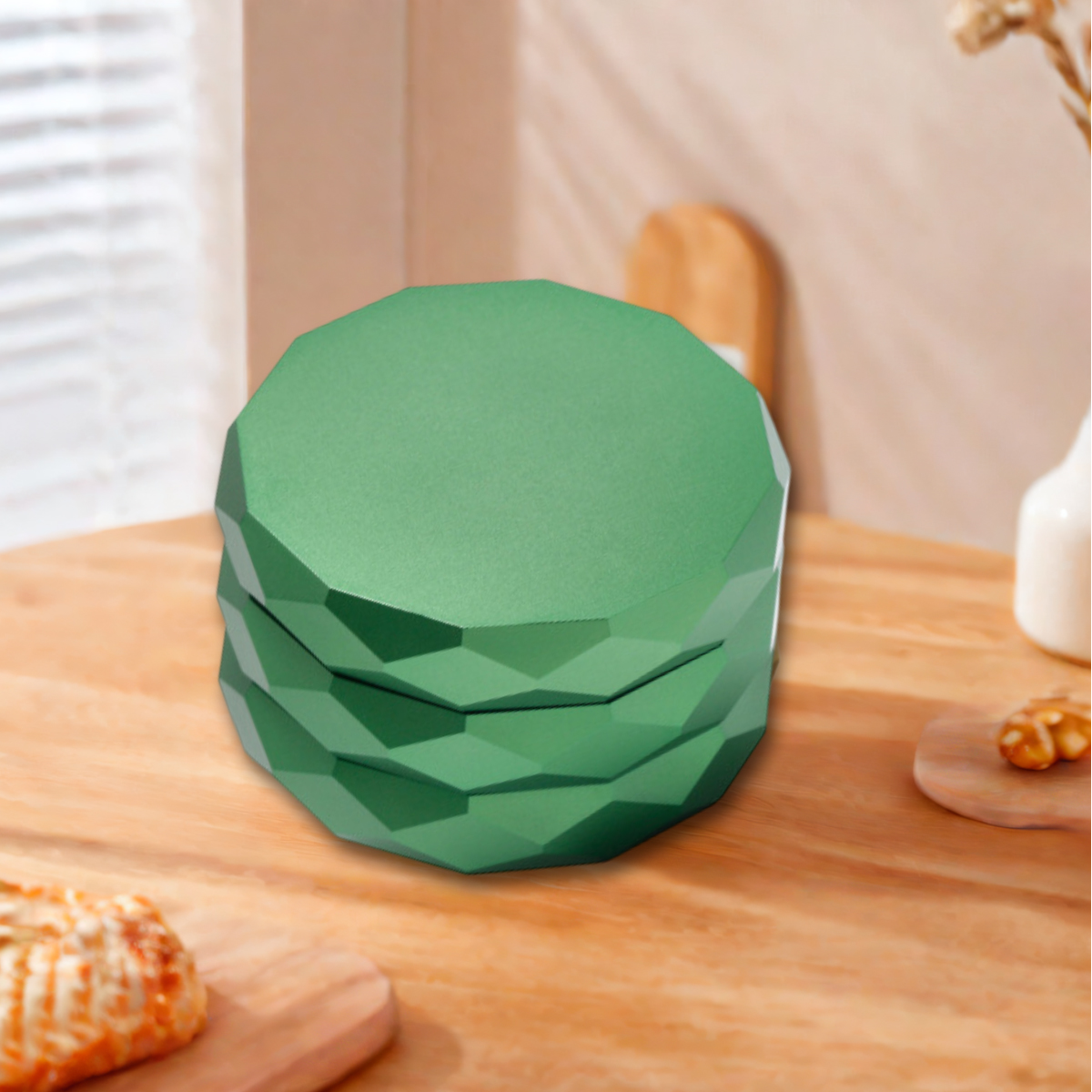 Ein grüner, geometrischer Behälter steht auf einem Holztisch. Weitere Gegenstände auf dem Tisch sind ein Schneidebrett mit einem Backwaren und eine Walnuss.