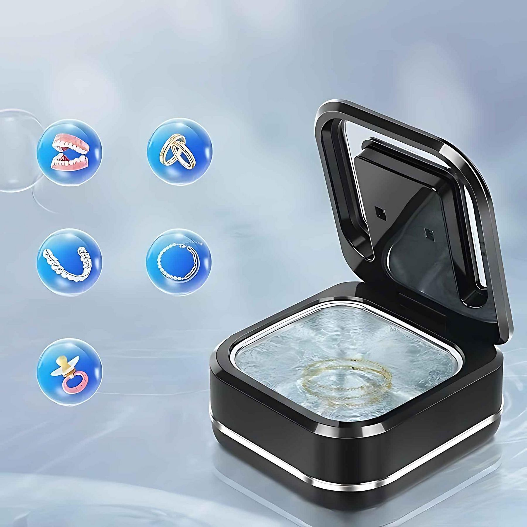 Ein schwarzer Schmuckreiniger mit offenem Deckel. Blasen mit Ringen, Zähnen, Zahnspangen, Halskette und Schnuller schweben herum.
