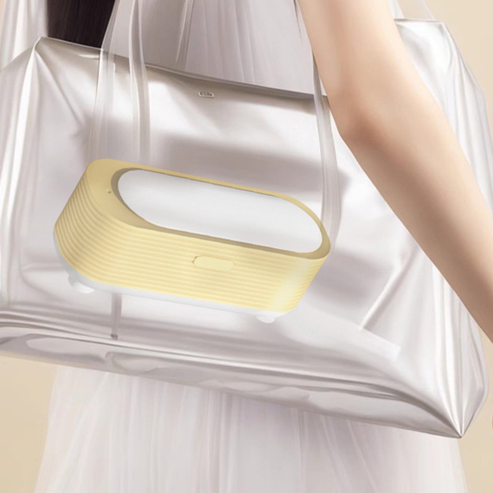 Ein gelbes Gerät mit weißer Oberseite befindet sich in einer transparenten Tasche, die von einem Arm gehalten wird.
