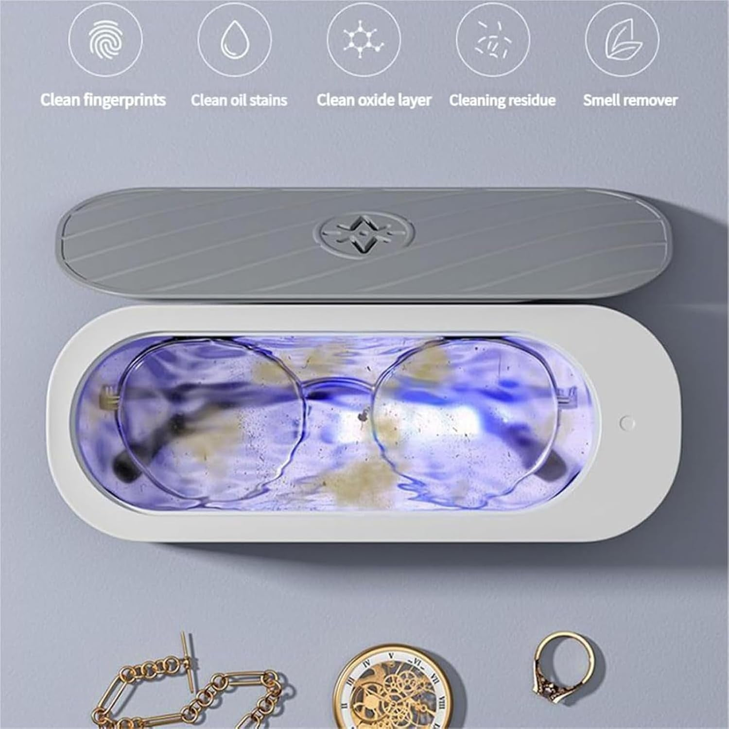 Brille in einem Reinigungsgerät mit Schmuck darunter. Oben sind Symbole zum Reinigen zu sehen. Das Gerät ist geöffnet und gibt blaues Licht ab.