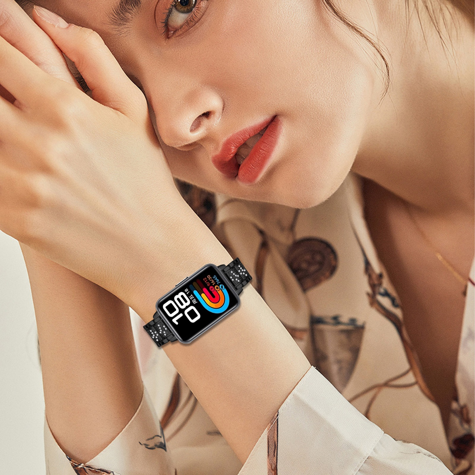 Eine Frau trägt eine Smartwatch. Die Uhr hat ein schwarzes Armband und ein farbenfrohes Display. Ihre Haut ist hell mit rotem Lippenstift.