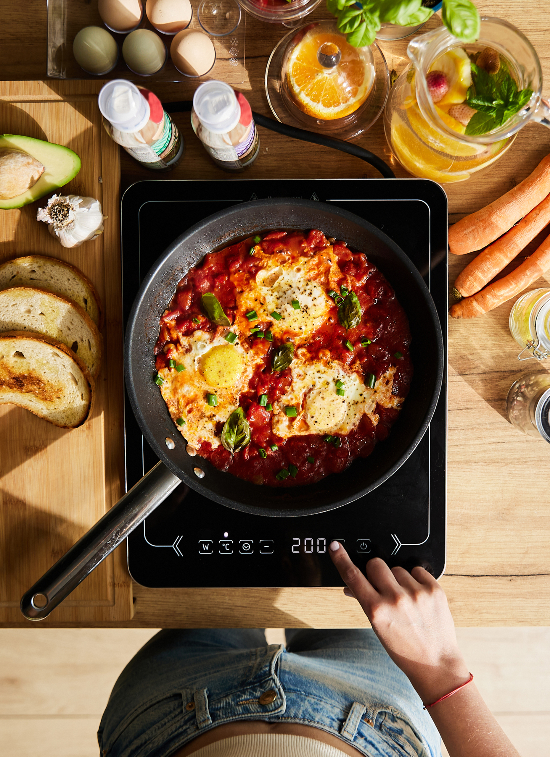 Widok z góry na gotowy posiłek, z jajkami w sosie pomidorowym i różnymi składnikami obok.