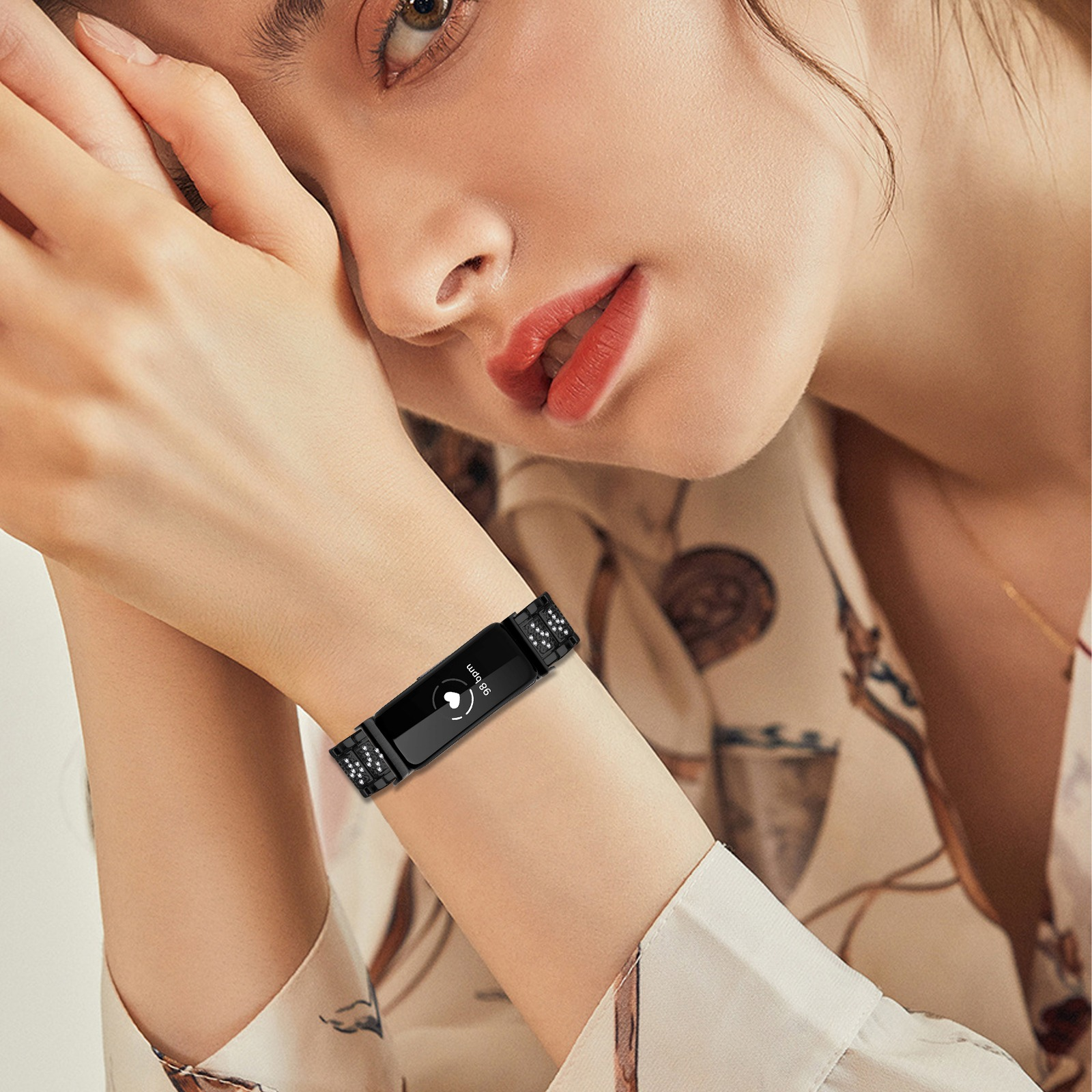 Eine Frau trägt einen schwarzen Fitness-Tracker. Ihre Hand ist in der Nähe ihres Gesichts. Sie trägt ein Hemd mit Blumenmuster.
