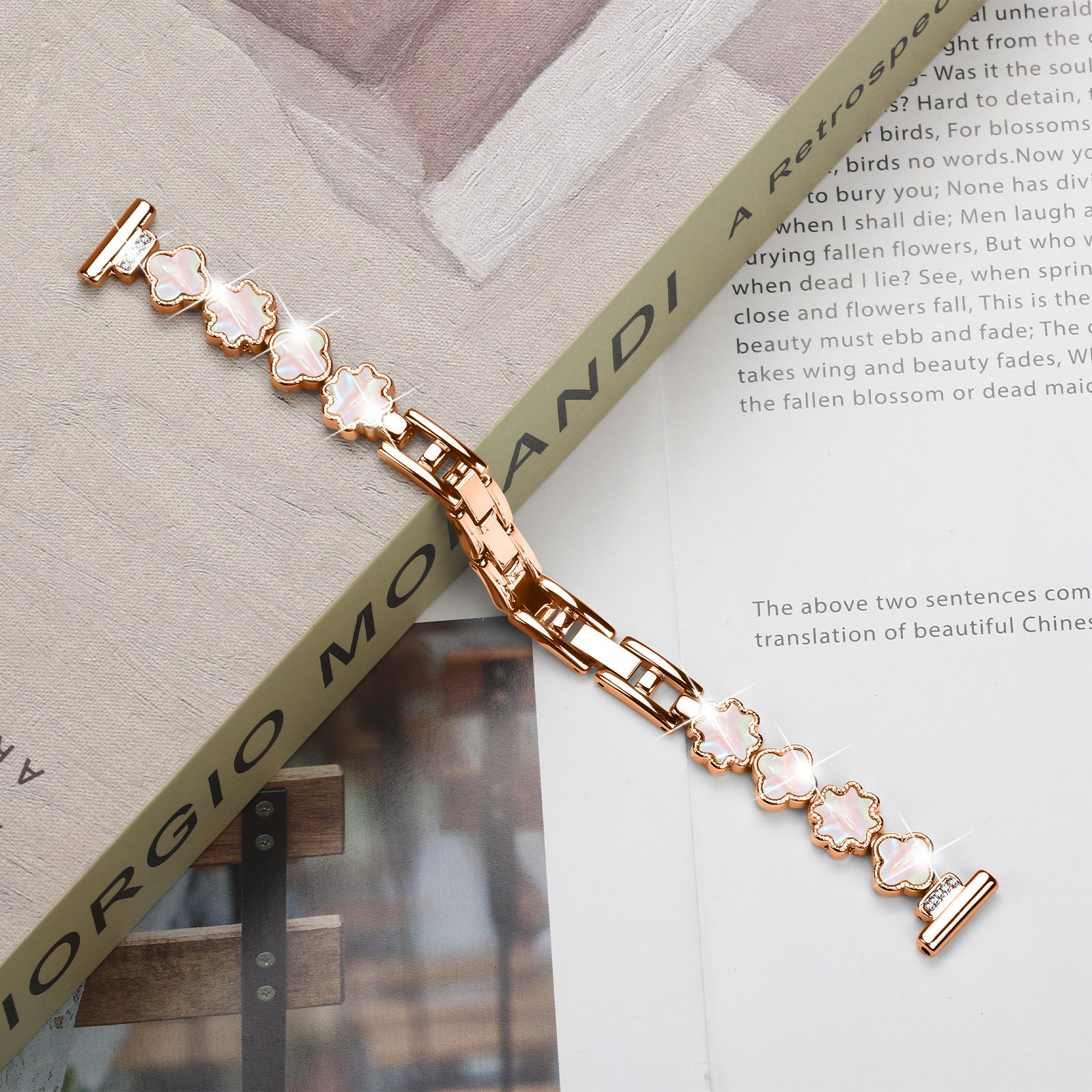 Ein roségoldenes Armband mit kleeblattförmigen Anhängern liegt auf einem Buch und einem Papier mit Text.