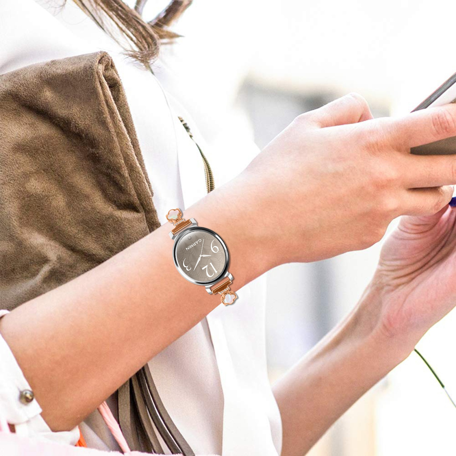 Eine Person mit einer Uhr hält ein Telefon. Die Uhr hat ein hellbraunes Armband. Auf der linken Seite befindet sich eine braune Handtasche.