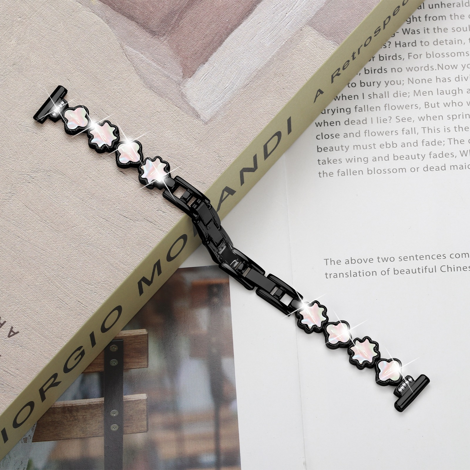 Un braccialetto nero con ciondoli a forma di fiore su un libro intitolato 'GIORGIO MOANDI' con testo.