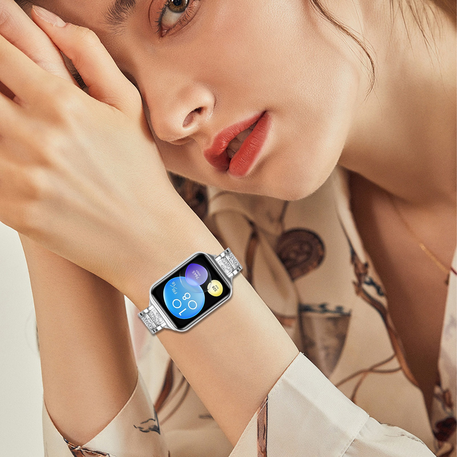 Donna con smartwatch argento con cinturino tempestato di diamanti, appoggia la mano vicino al viso.