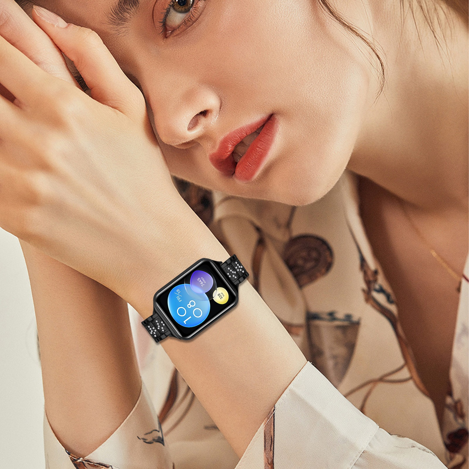 Frau mit schwarzer Smartwatch. Die Uhr zeigt Zeit und Gesundheitsdaten an. Sie trägt ein gemustertes Hemd.