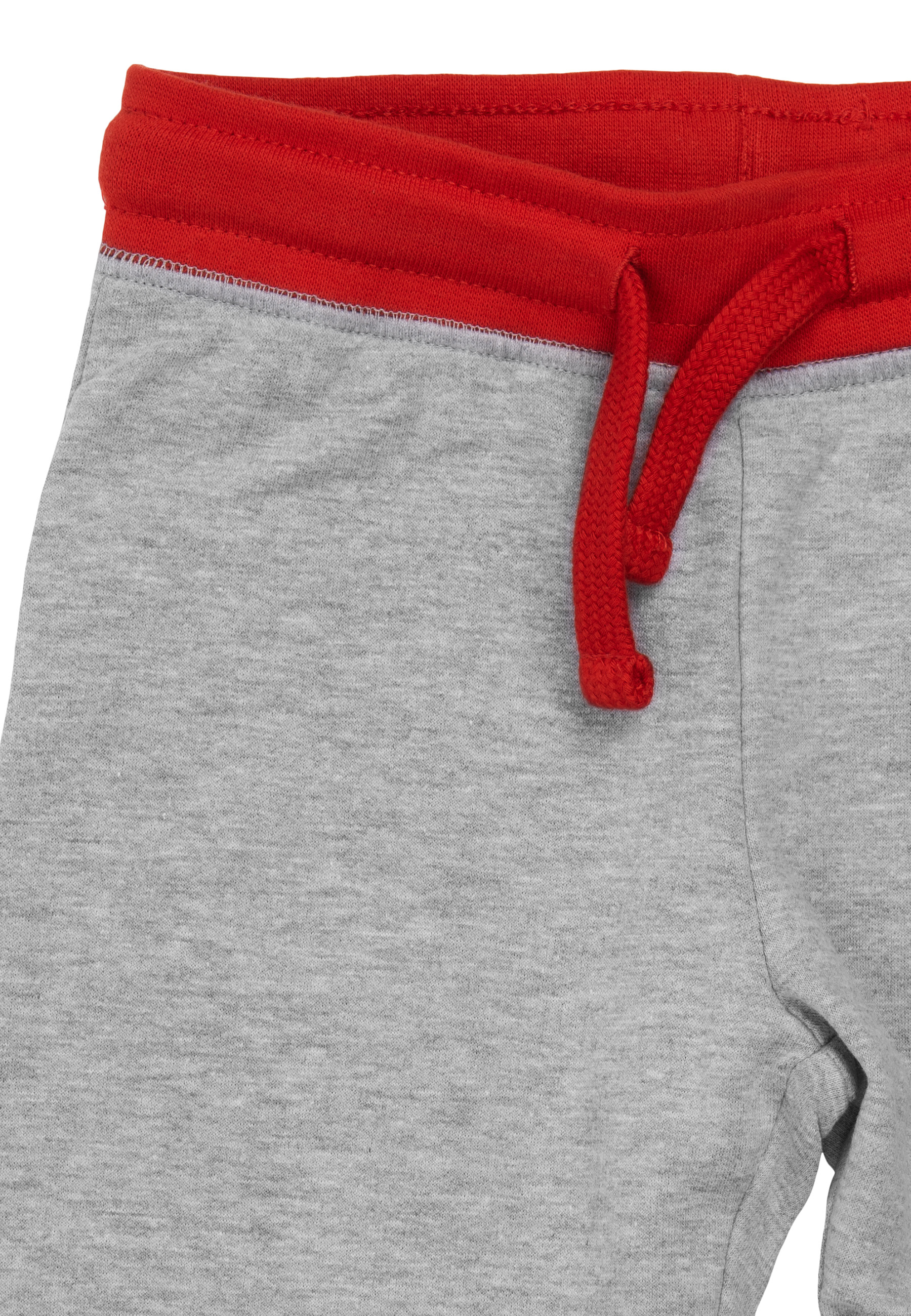 Nahaufnahme einer grauen Jogginghose mit rotem Bund und Kordelzug. Der Stoff ist mit weißem Hintergrund sichtbar.