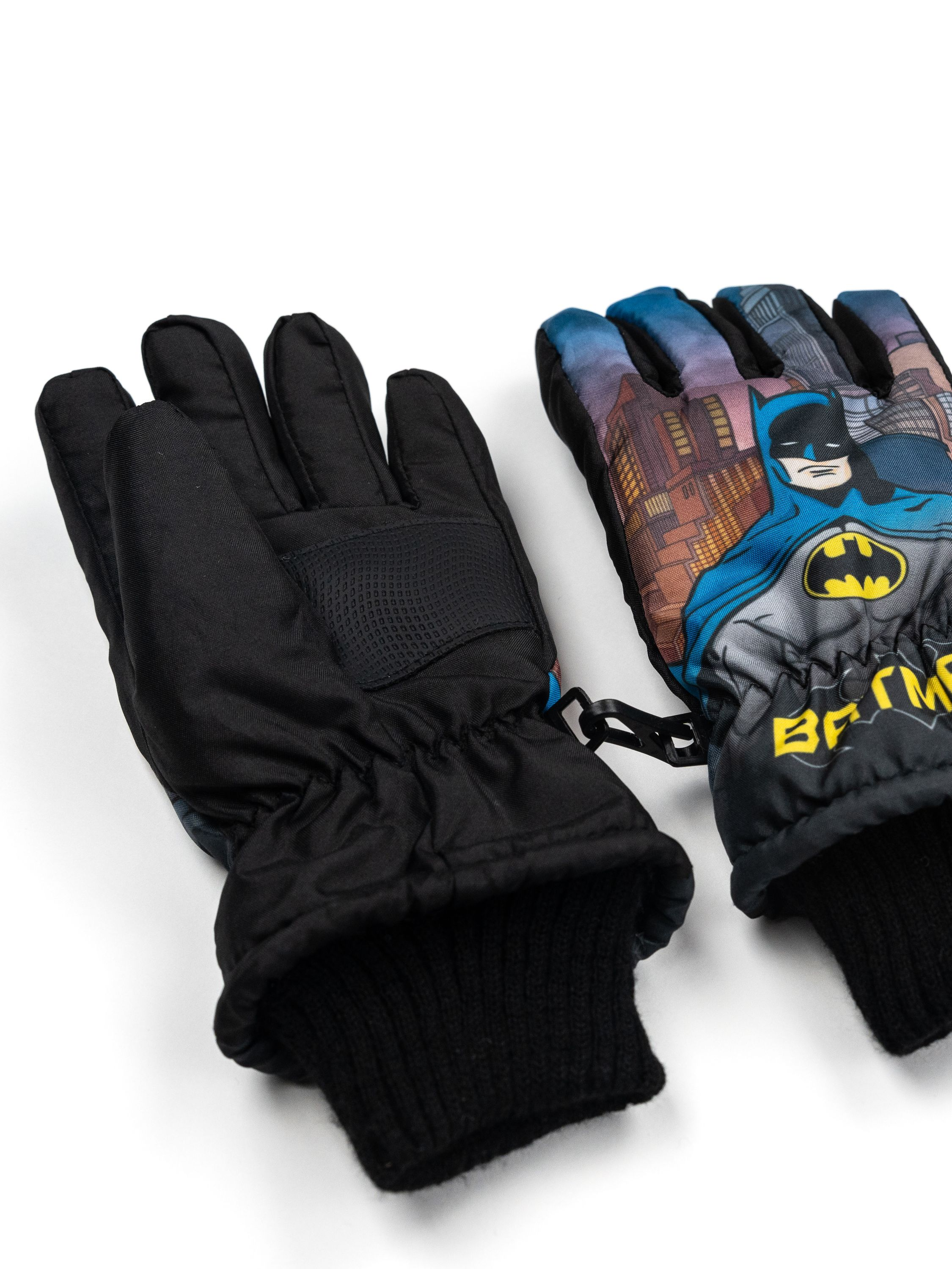 Paar schwarze Batman-Handschuhe mit Batman-Logo und Stadtszene auf dem rechten Handschuh, isoliert auf weißem Hintergrund.