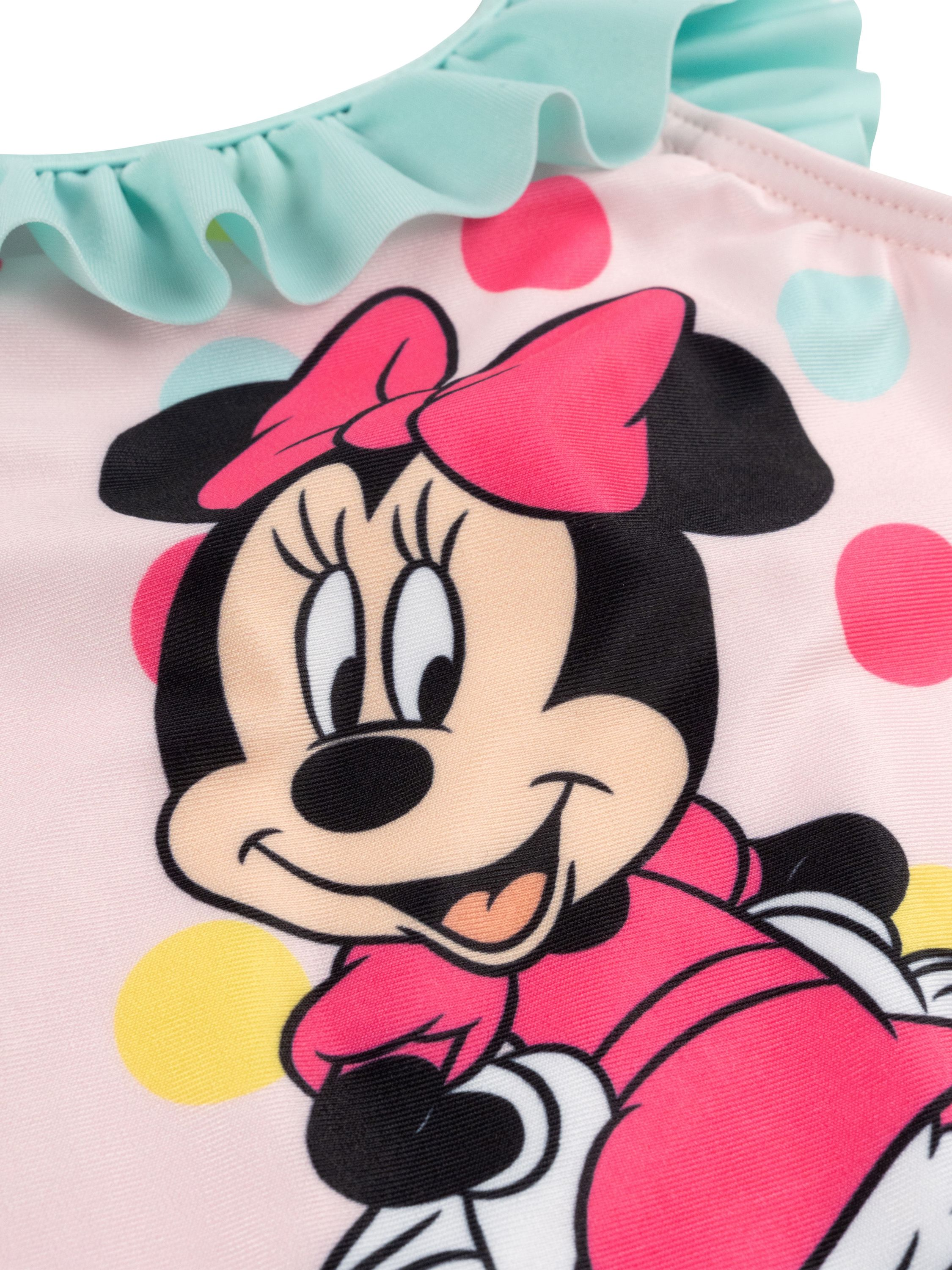 Nahaufnahme eines pinkfarbenen Badeanzugs mit Minnie Mouse. Er hat eine mintgrüne Rüsche und Tupfen.