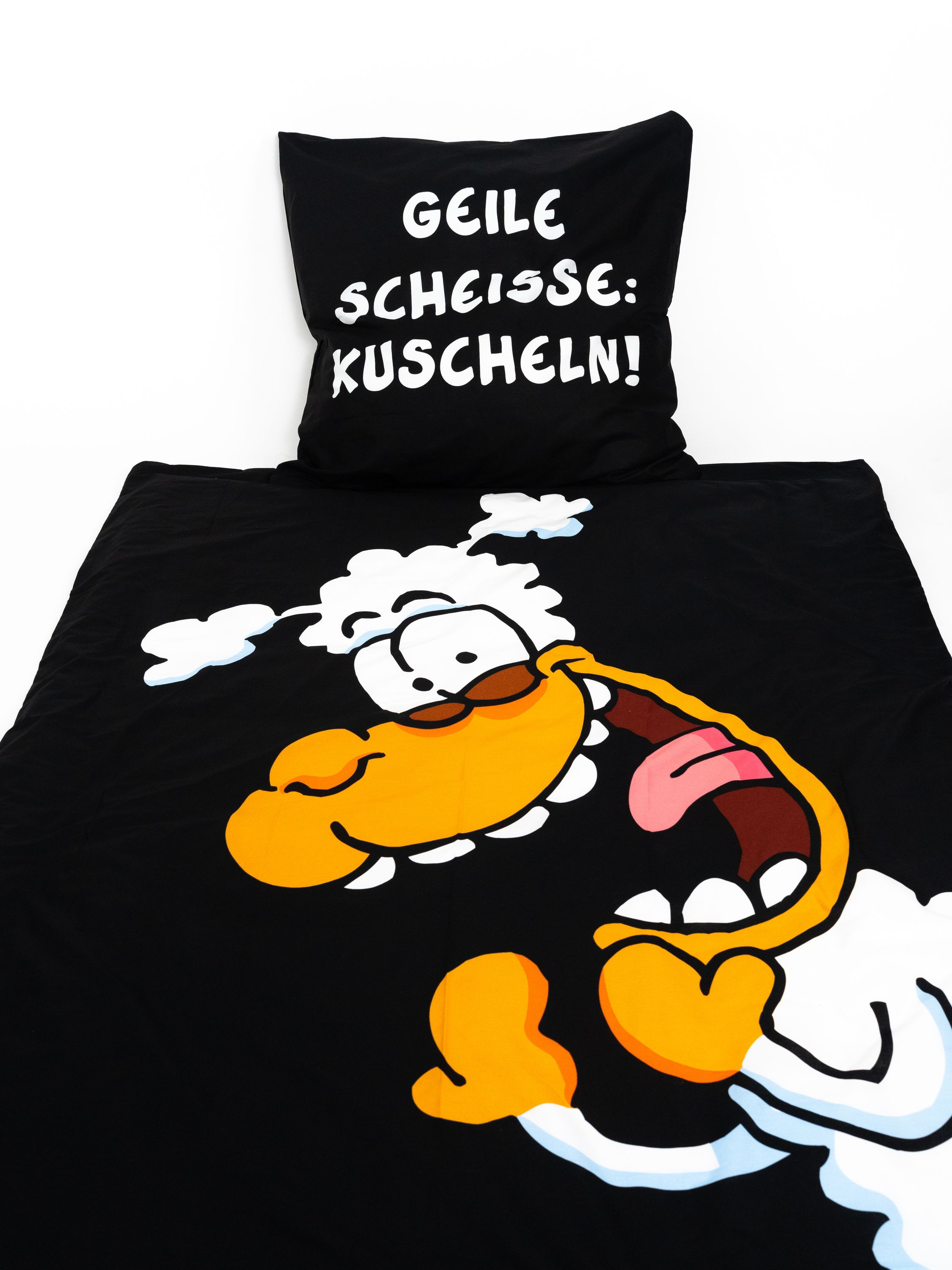Schwarze Bettwäsche mit einem Cartoon-Schaf und dem Text 'GEILE SCHEISSE: KUSCHELN!' in Weiß.