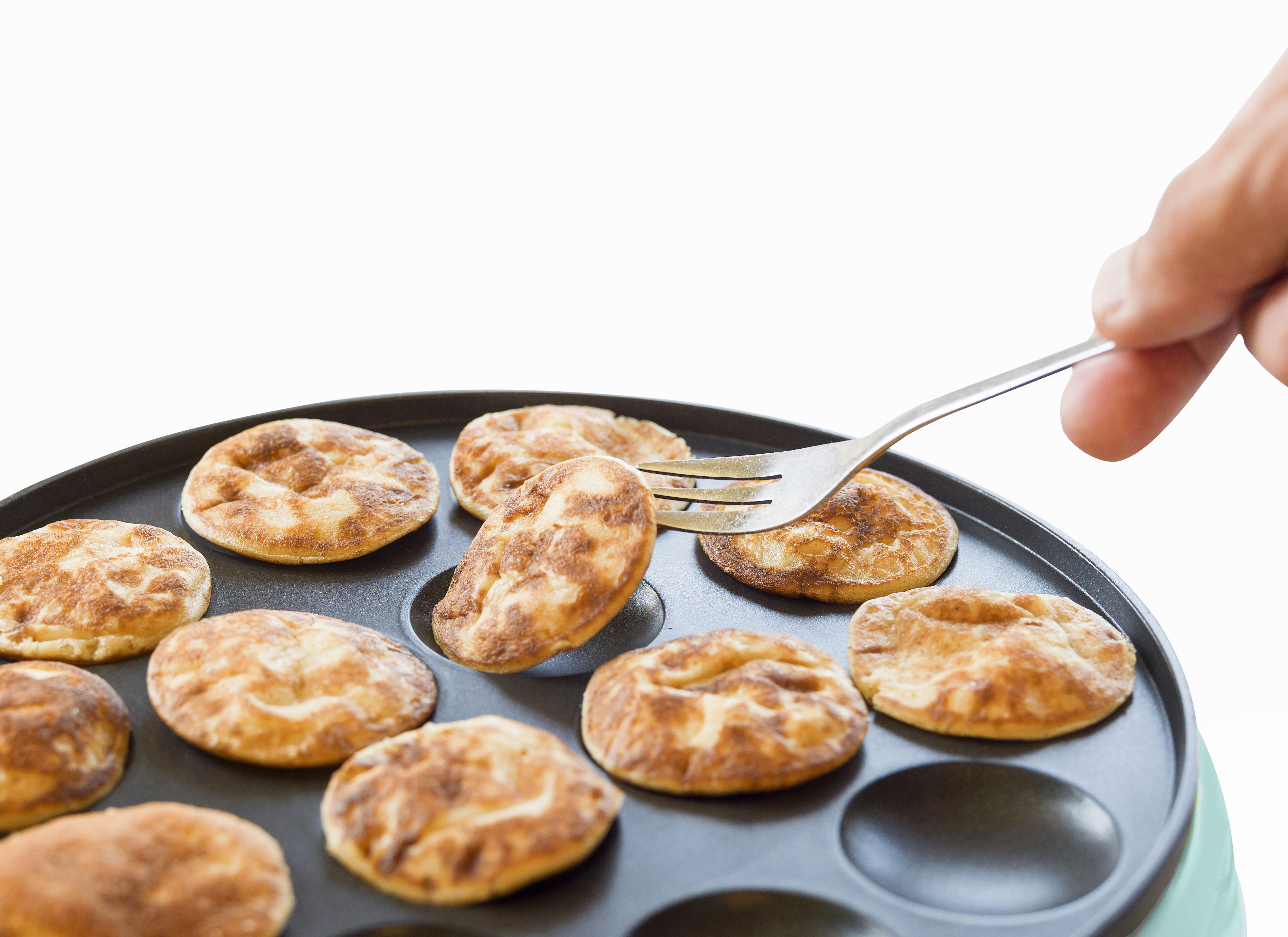 Naleśniki na patelni podnoszone widelcem. Naleśniki są złocistobrązowe i okrągłe. Ręka po prawej.