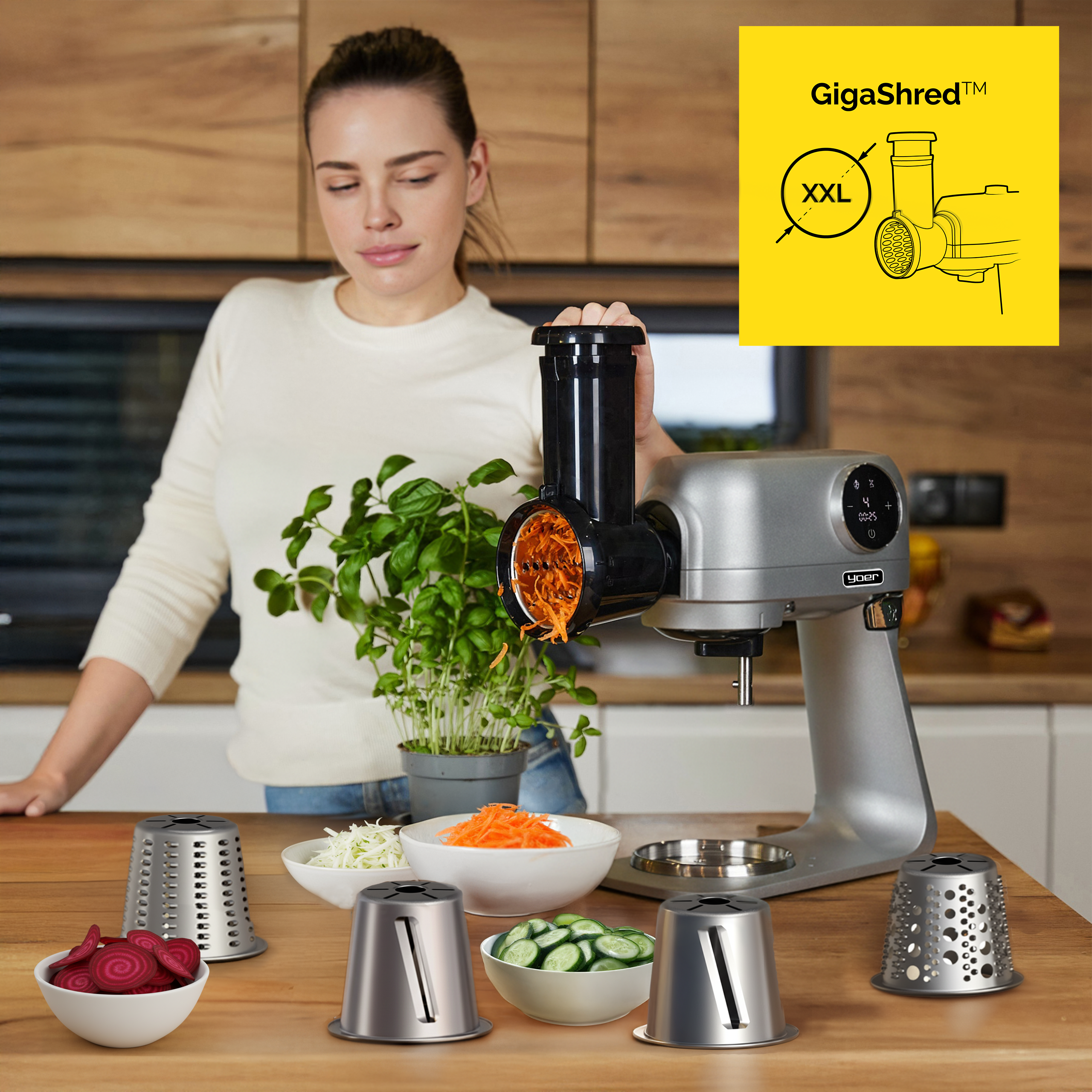 Kobieta używa srebrnego robota kuchennego do ścierania marchewki. Miski z warzywami i ostrza na drewnianym blacie.
