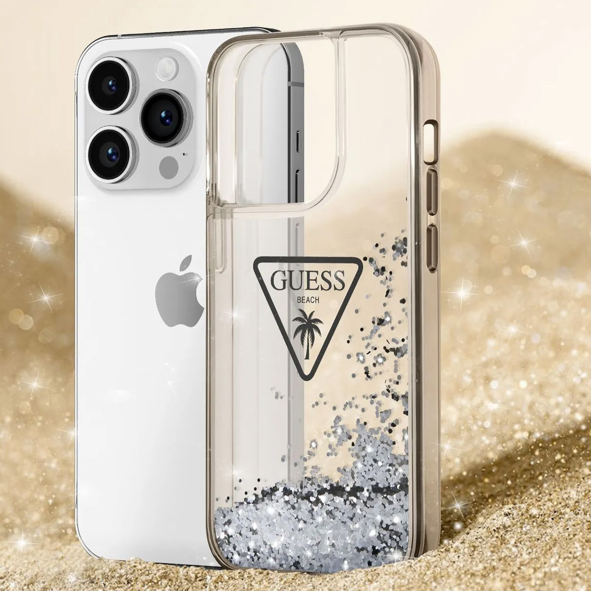 Un iPhone con custodia Guess trasparente piena di glitter argentati, su sfondo sabbioso e scintillante.