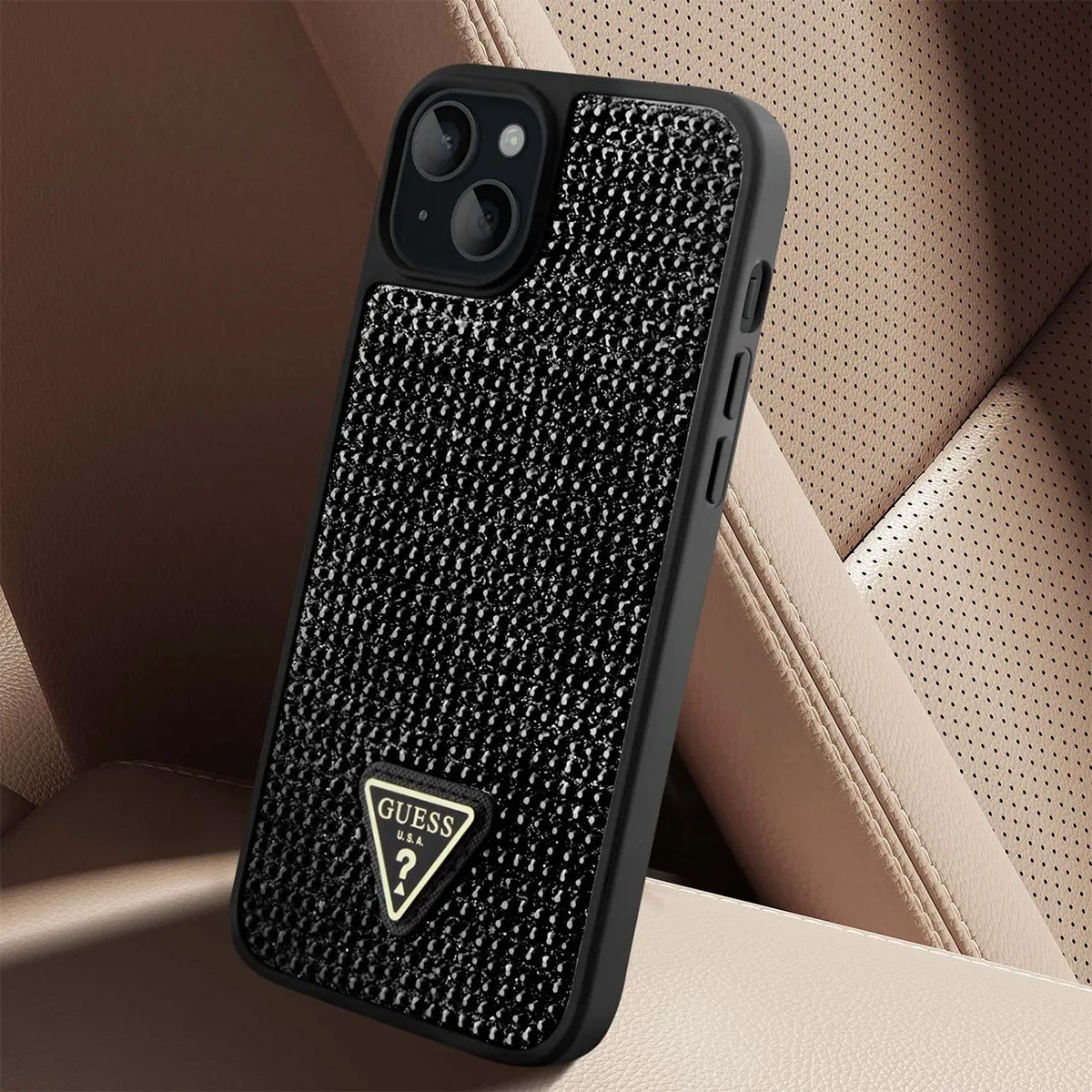 Custodia per telefono nera con logo Guess, su un sedile auto beige. La custodia ha una superficie strutturata e una cornice nera.
