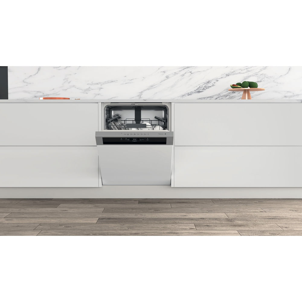 Una cucina moderna con lavastoviglie. Lo sportello della lavastoviglie è aperto. Pavimento in legno e armadi bianchi. Lo sfondo ha frutta.