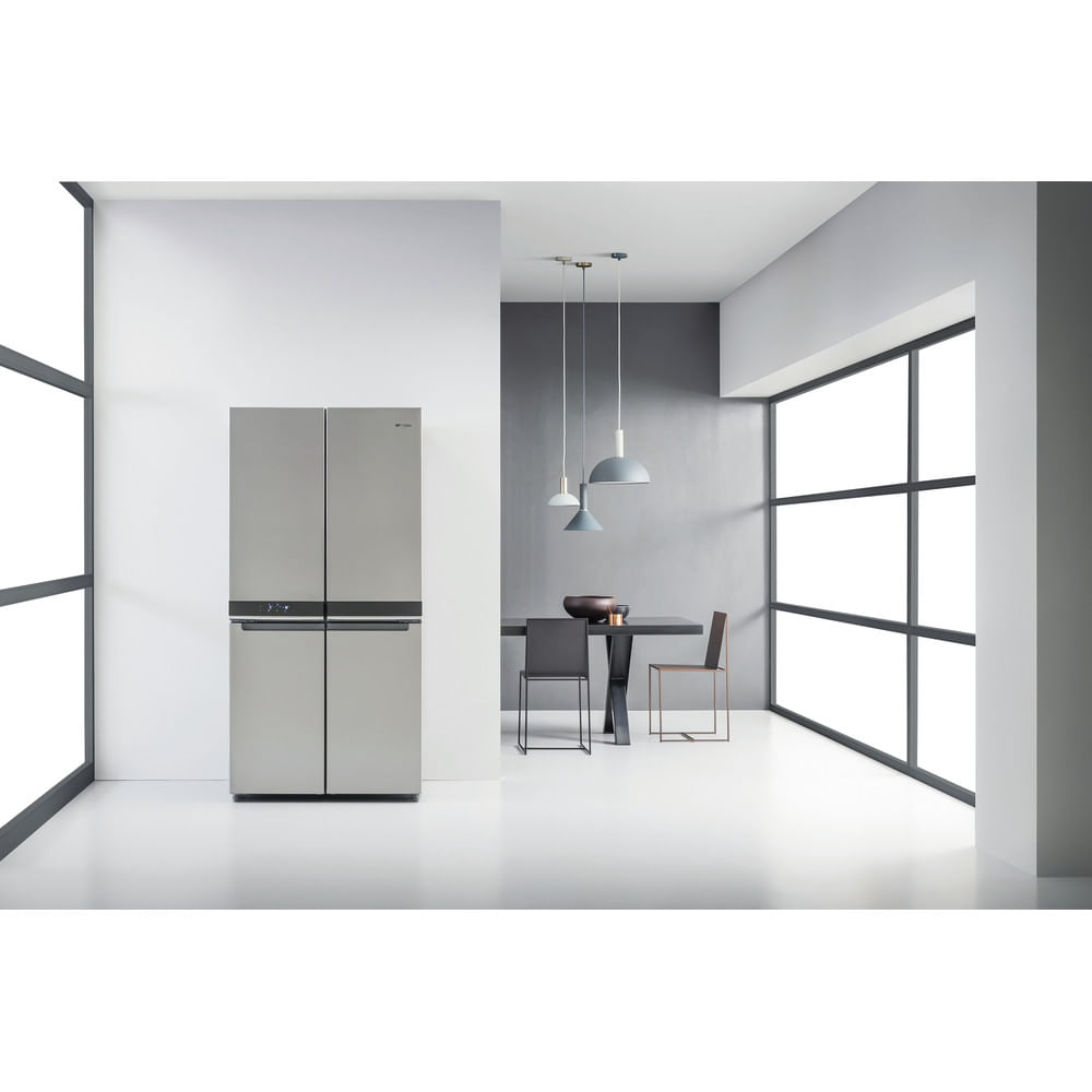Una cocina moderna con un gran refrigerador de acero inoxidable. Hay una mesa con dos sillas. Las ventanas están al lado.