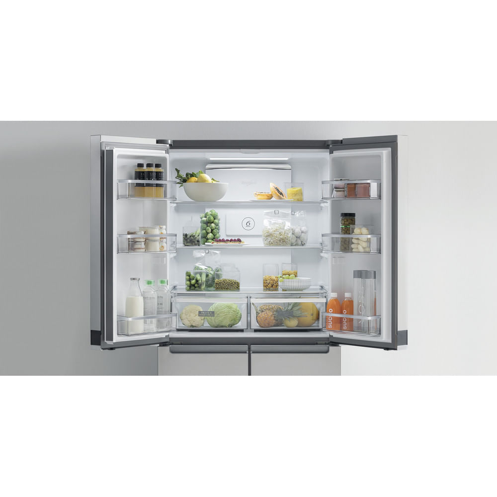 Refrigerador abierto lleno de frutas, verduras y bebidas. Se ven contenedores y estantes transparentes. El refrigerador es de acero inoxidable.