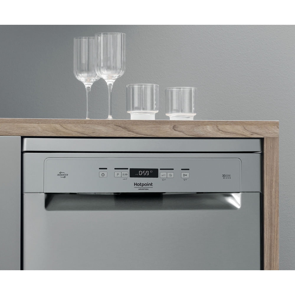 Un lavavajillas con vasos encima. La pantalla muestra 0:59. La marca es Hotpoint Ariston.