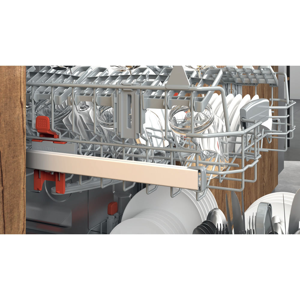 Se muestra el interior de un lavavajillas, lleno de vasos, platos y cubiertos. Las rejillas son de metal y el fondo es de madera.