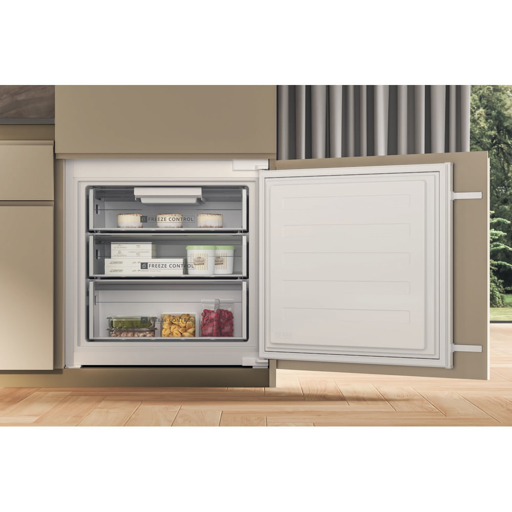 Un congelatore moderno con la porta aperta. All'interno, tre cassetti contengono alimenti come gelato e surgelati.