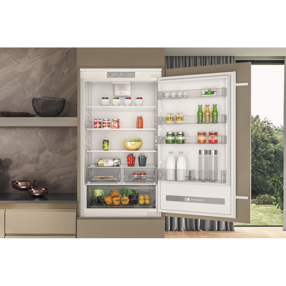 Frigorifero aperto che mostra alimenti. Frutta, verdura e barattoli sono visibili. La porta è socchiusa, rivelando il contenuto.