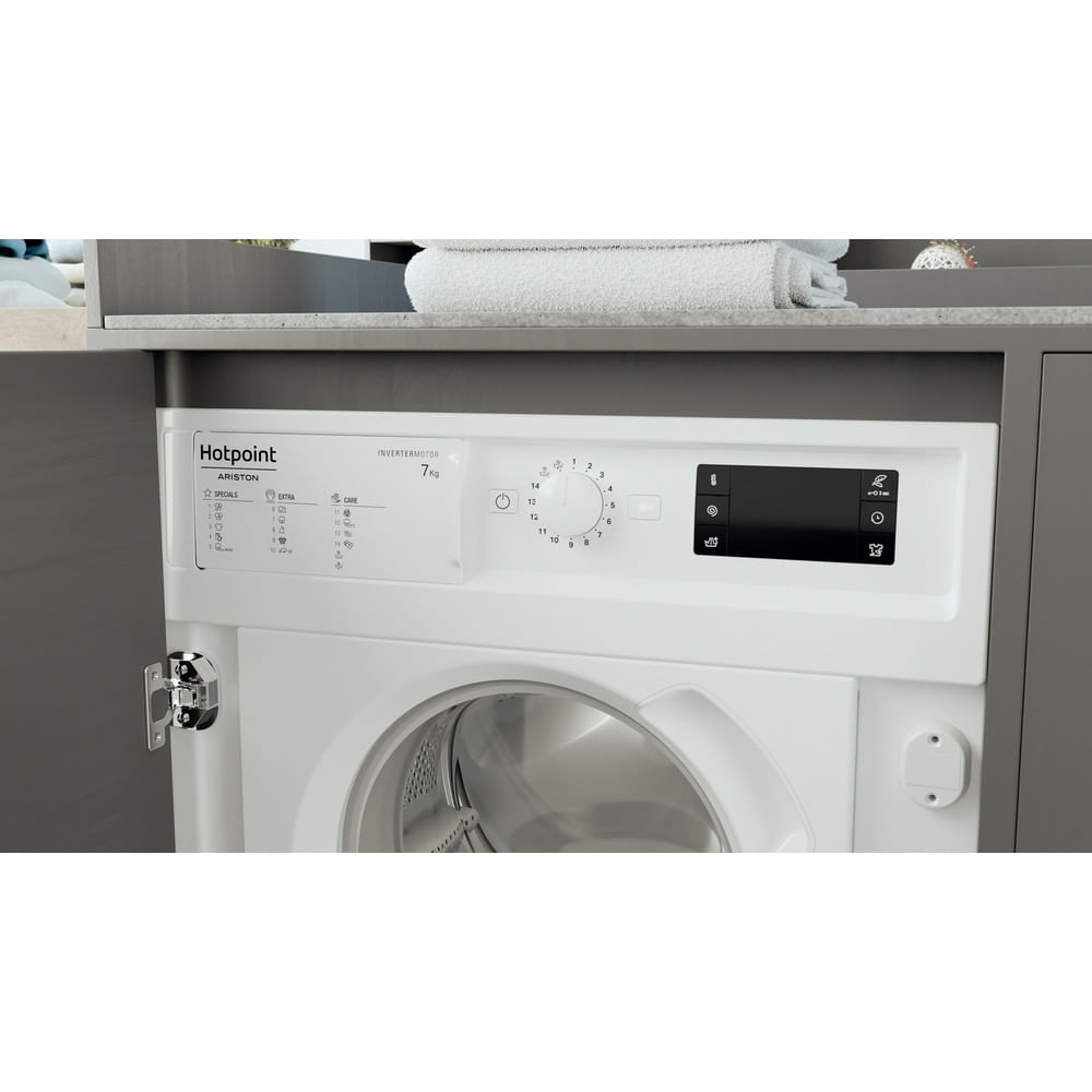 Viene mostrata una lavatrice Hotpoint bianca. Ha un pannello di controllo con manopole e un display digitale. Un asciugamano è sopra.