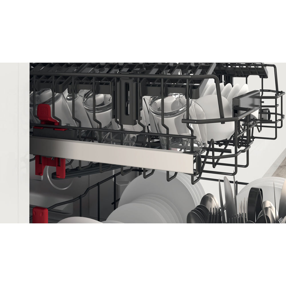 Wnętrze zmywarki ze szklankami, talerzami i sztućcami. Czarne kosze trzymają naczynia, widoczne czerwone elementy. Białe, czyste talerze są ułożone.