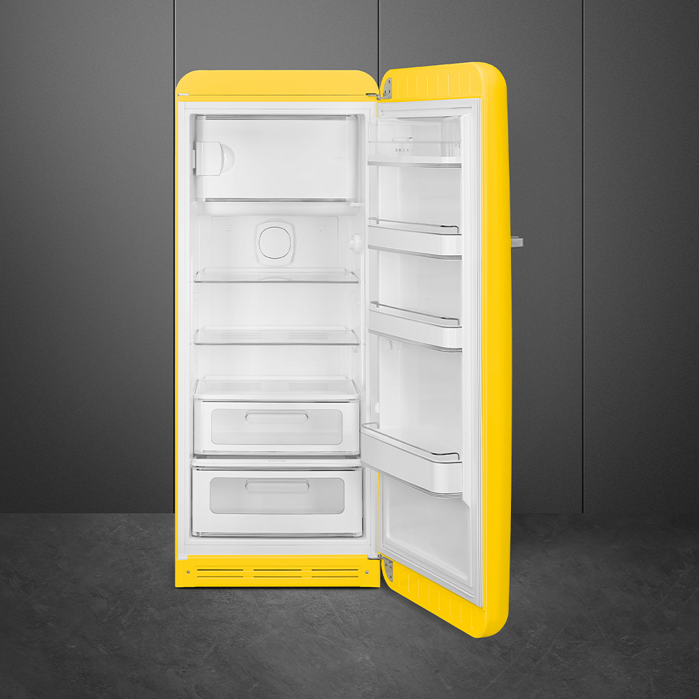 Un refrigerador retro amarillo con la puerta abierta, revelando estantes y cajones interiores blancos. El fondo es gris.