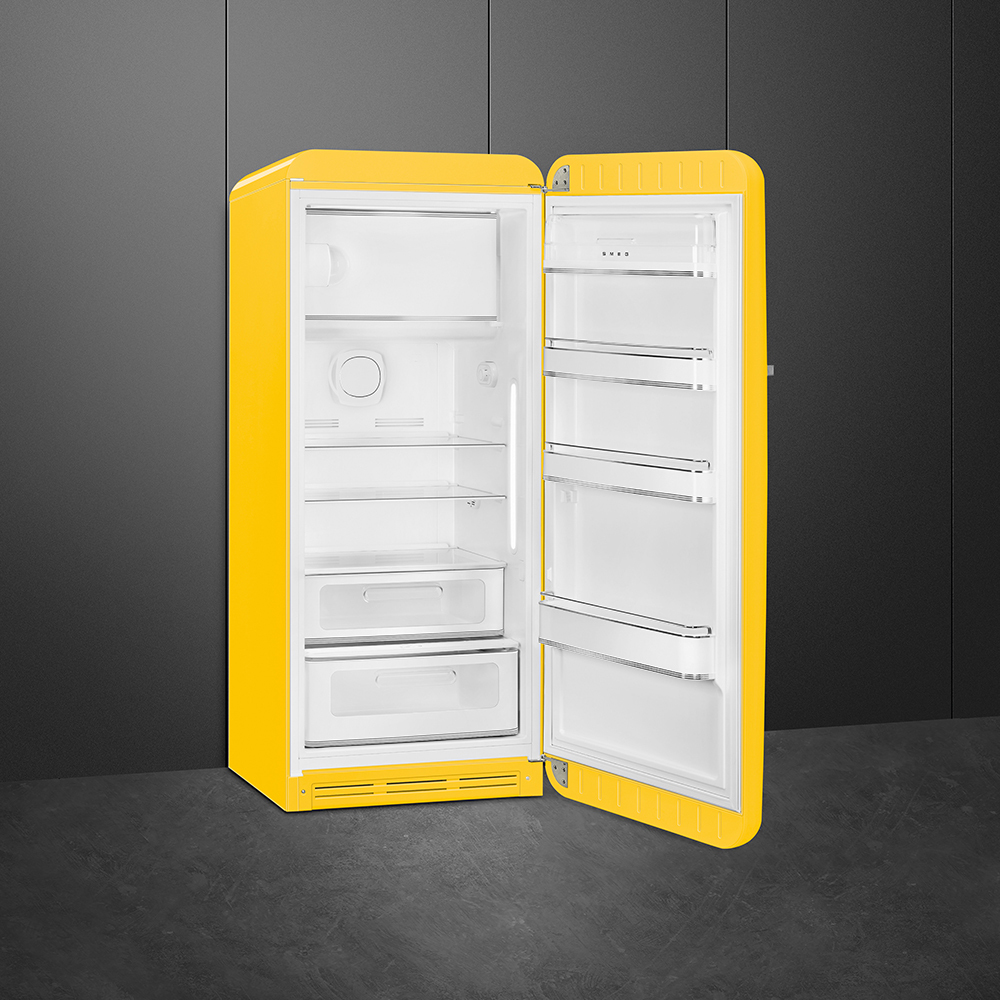 Un refrigerador retro amarillo con la puerta abierta. El interior es blanco con estantes. Está contra un fondo gris oscuro.