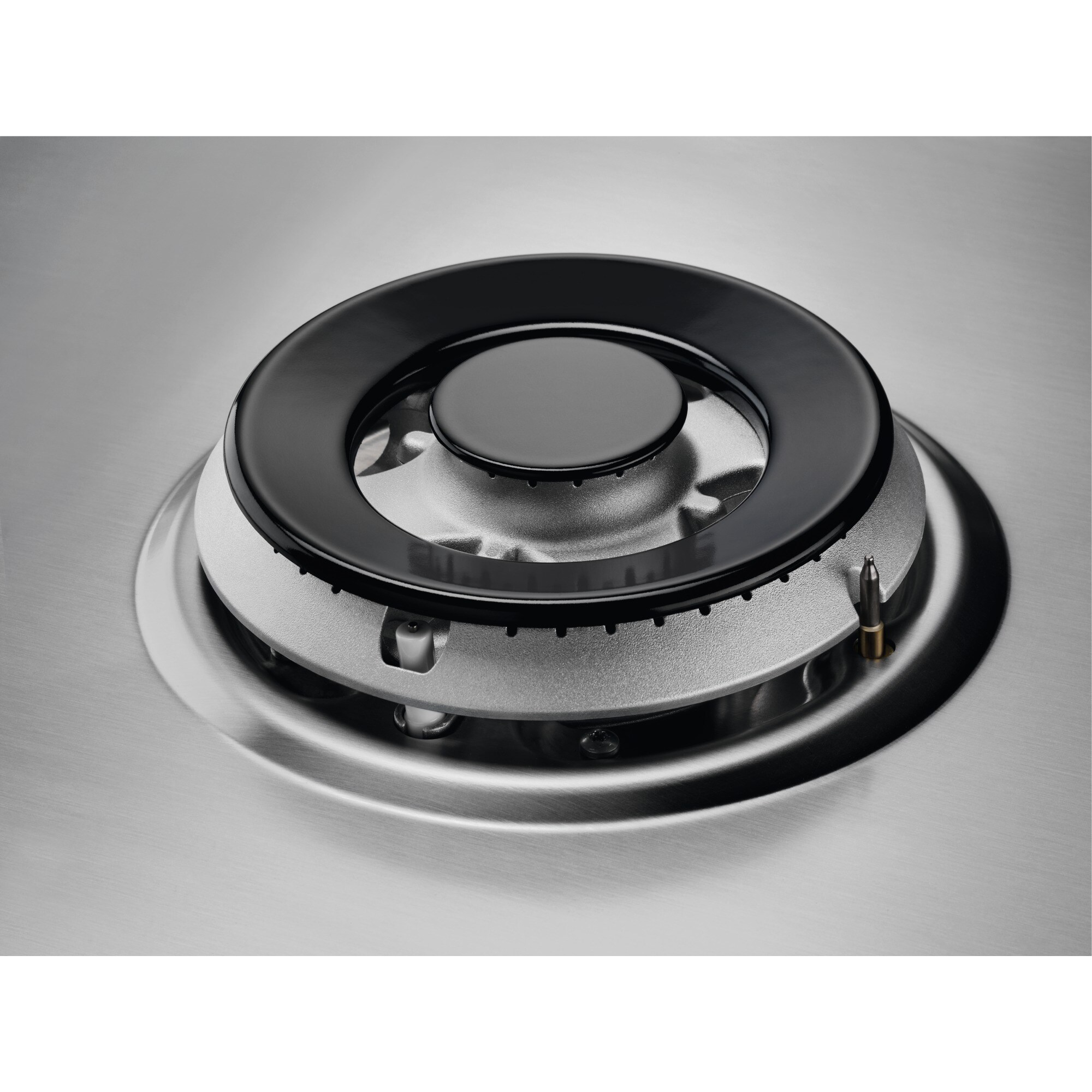 Zbliżenie palnika kuchenki z czarnym pierścieniem, srebrnym palnikiem i powierzchnią ze szczotkowanego metalu.