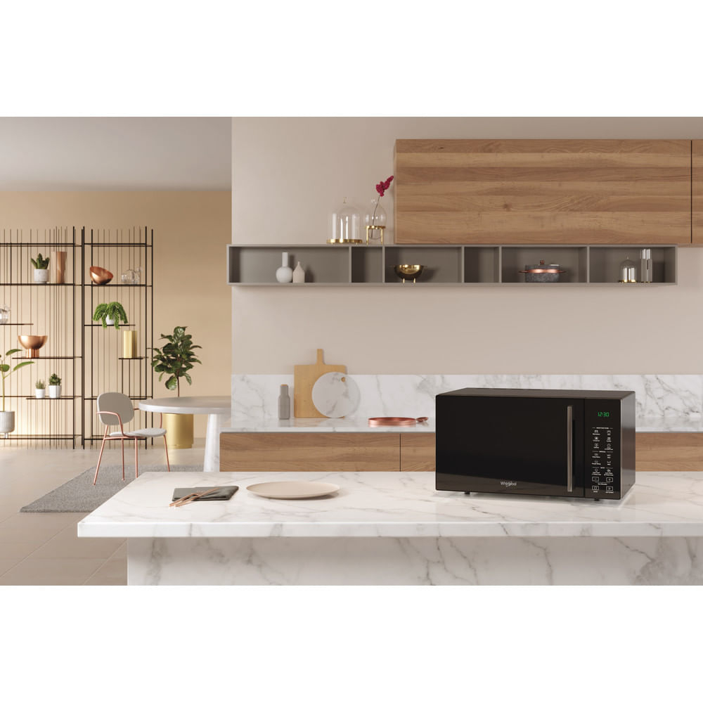 Nowoczesna kuchnia z czarną kuchenką mikrofalową na marmurowym blacie. Półki, stół i dekoracje w tle.