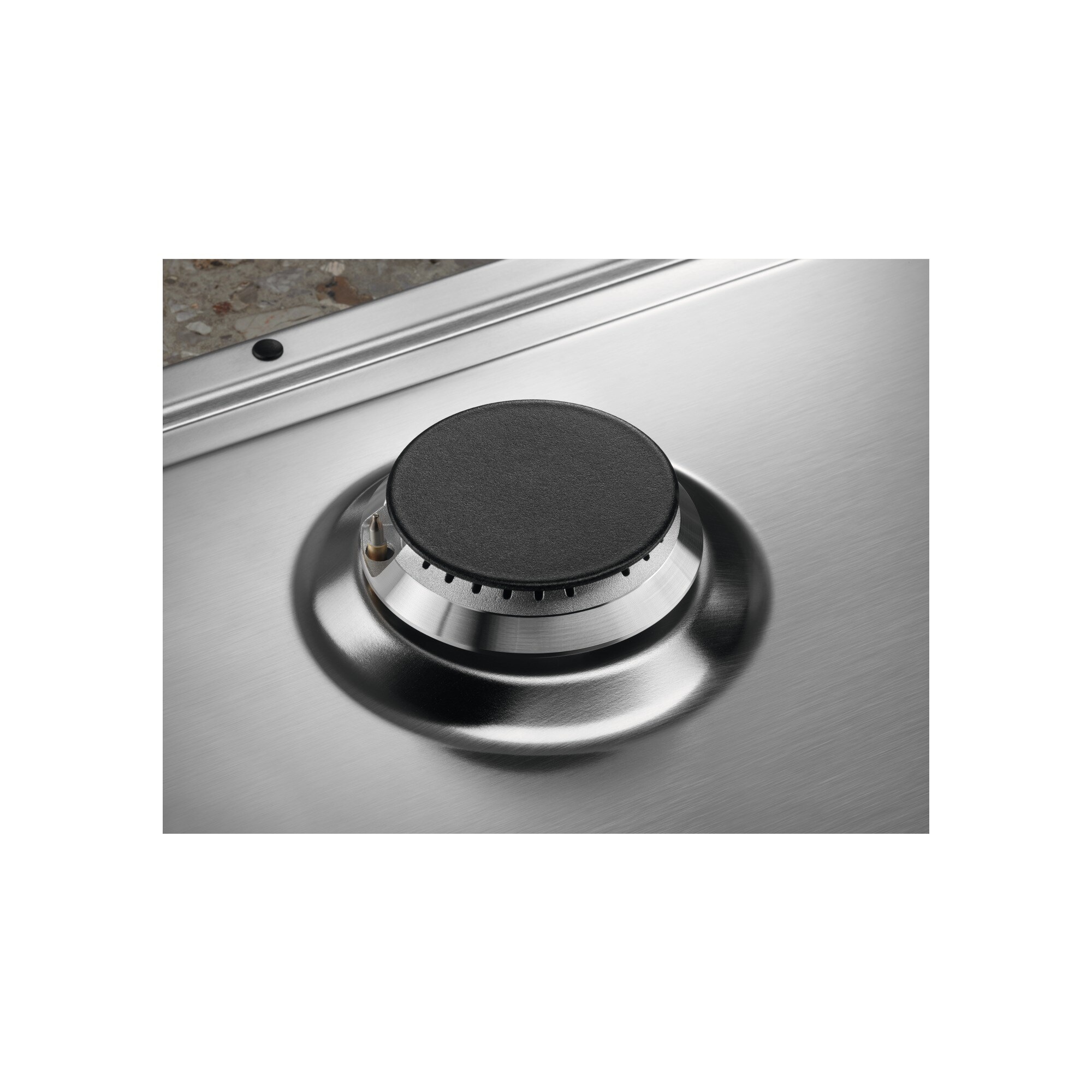 Zbliżenie palnika kuchenki gazowej ze stali nierdzewnej. Palnik ma czarną okrągłą nasadkę i srebrną metalową podstawę.