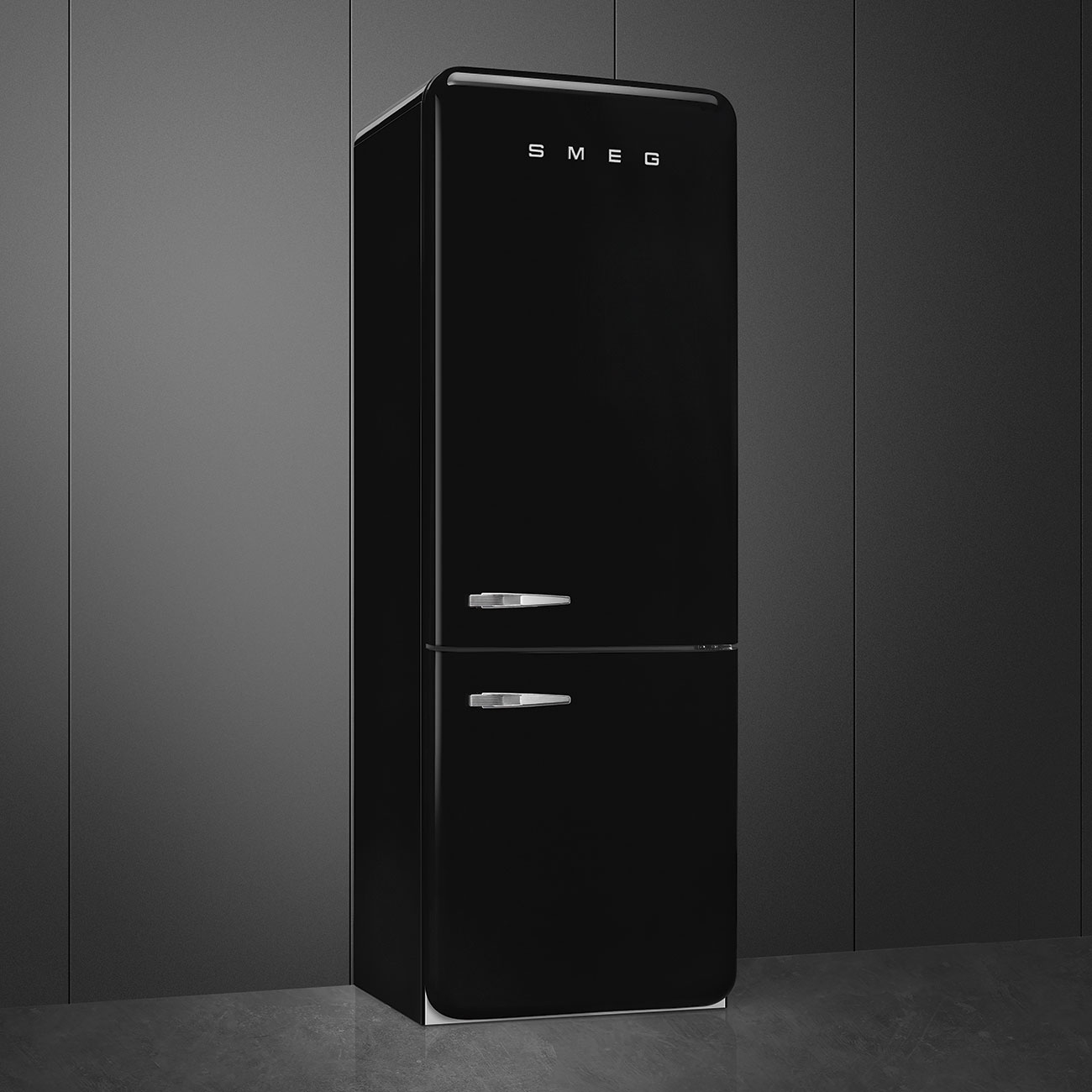 Un refrigerador Smeg negro se alza contra una pared gris oscura. Tiene dos puertas y manijas cromadas. La marca es visible.