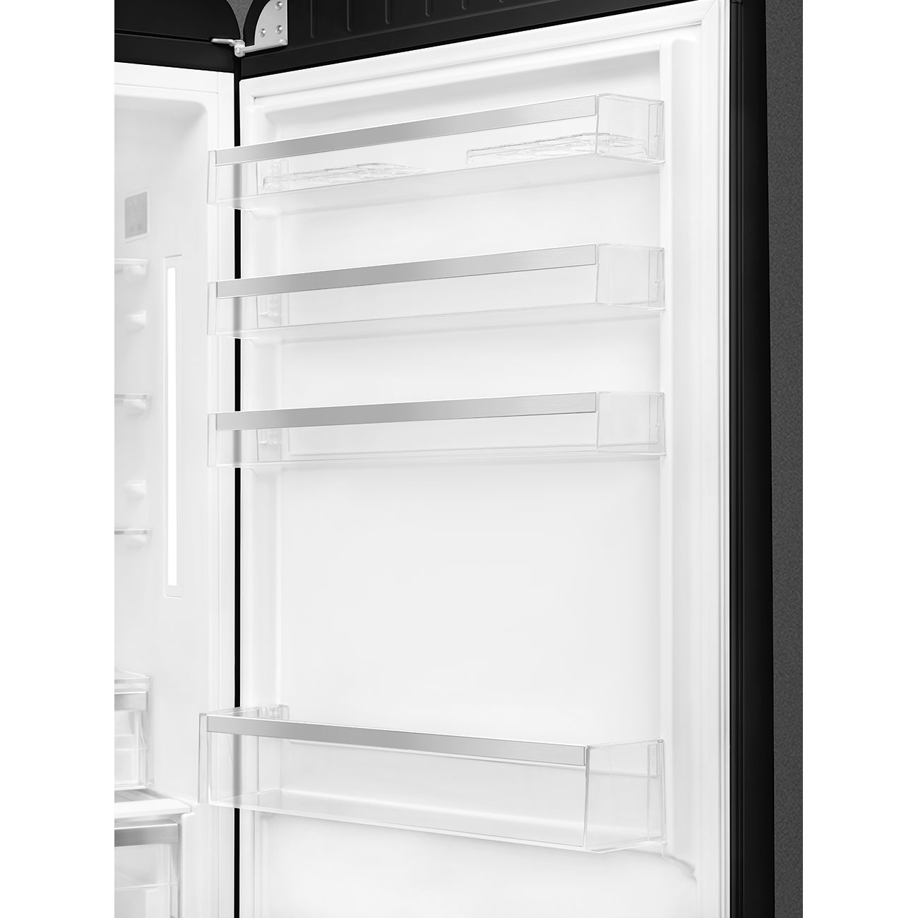 Una puerta de refrigerador abierta revela estantes vacíos con molduras plateadas. El interior es blanco, el marco de la puerta negro y las bisagras son visibles.