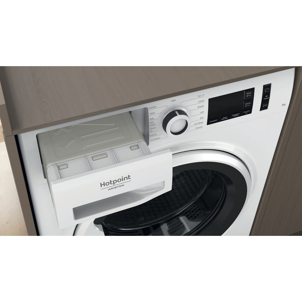Una lavatrice bianca Hotpoint Ariston con cassetto detersivo aperto. La macchina è in un mobile di legno.