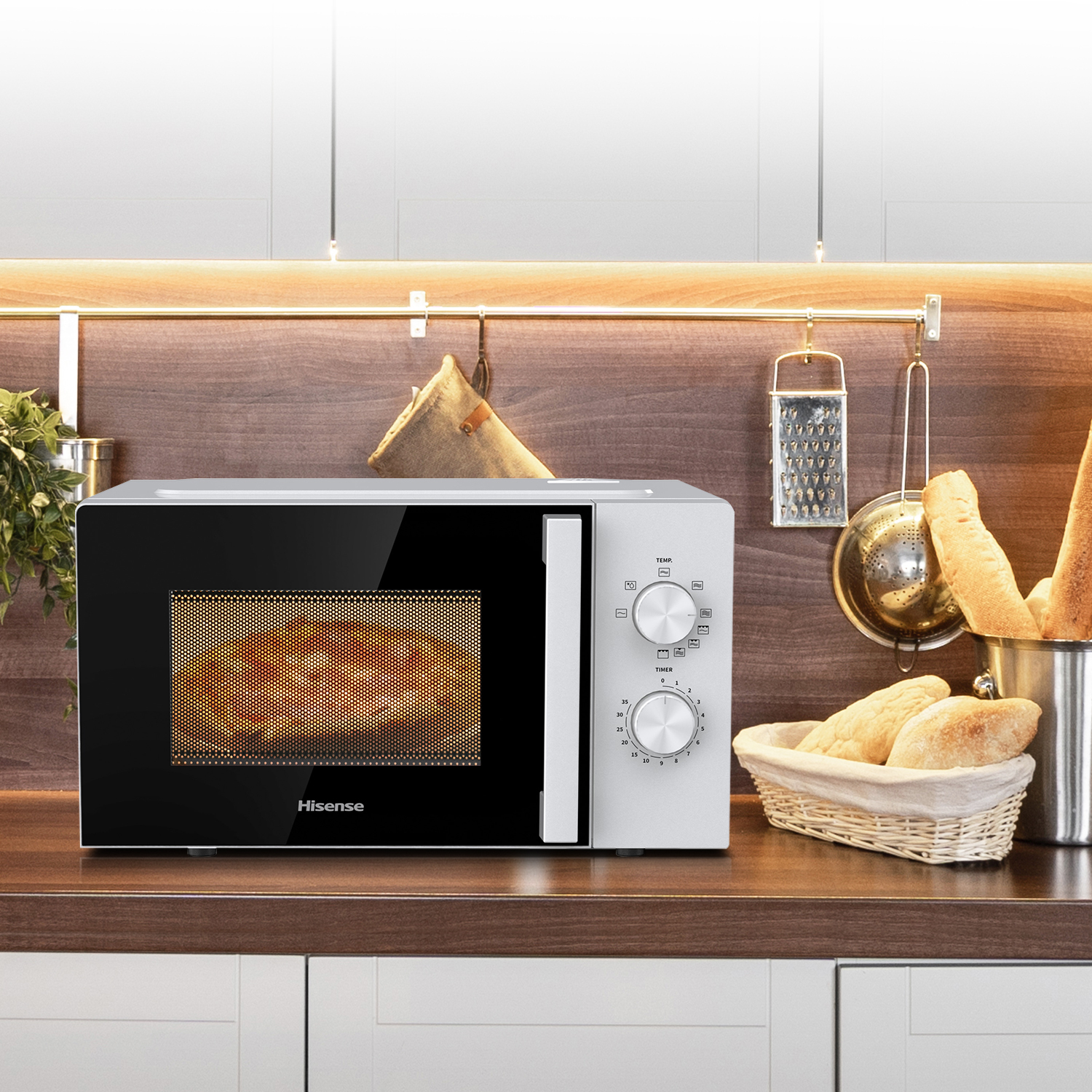 Eine Hisense-Mikrowelle mit Essen, einem Timer und Temperaturreglern, mit Brot und Küchenutensilien im Hintergrund.
