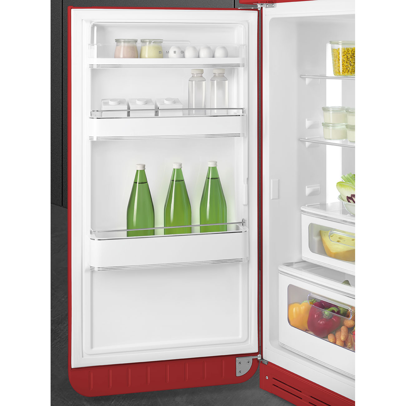 Refrigerador rojo abierto con estantes. Contiene botellas, lácteos, verduras y recipientes. Interior blanco.