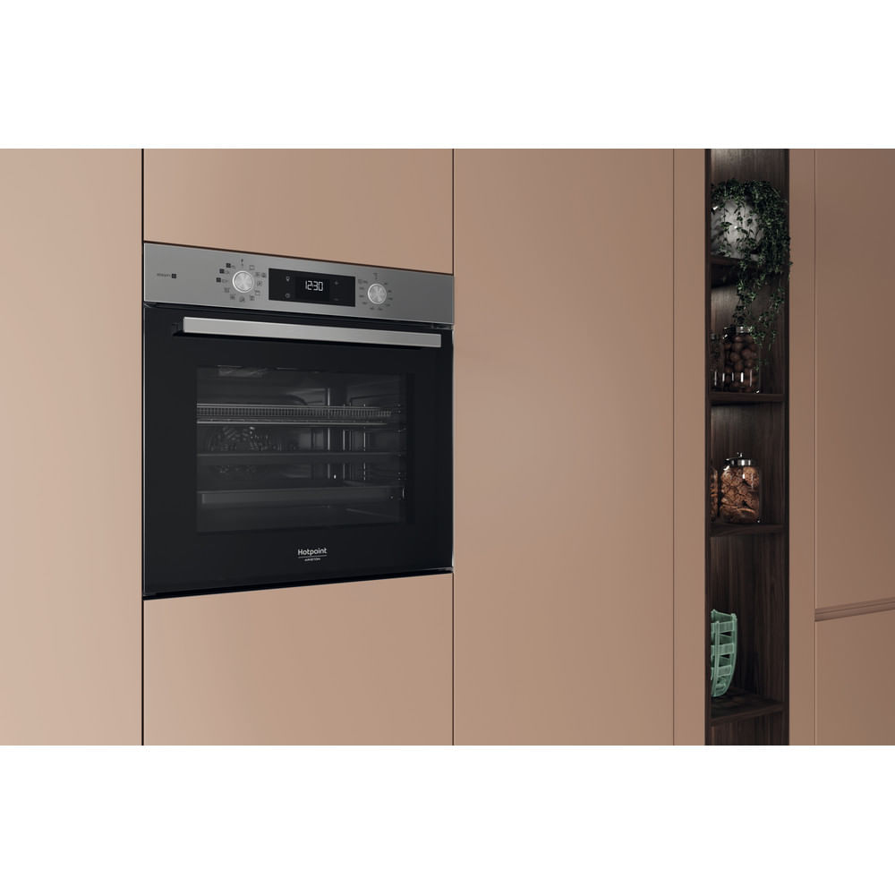 Cucina moderna con forno a incasso e display dell'ora. Armadi su entrambi i lati. Mensole decorative a destra.