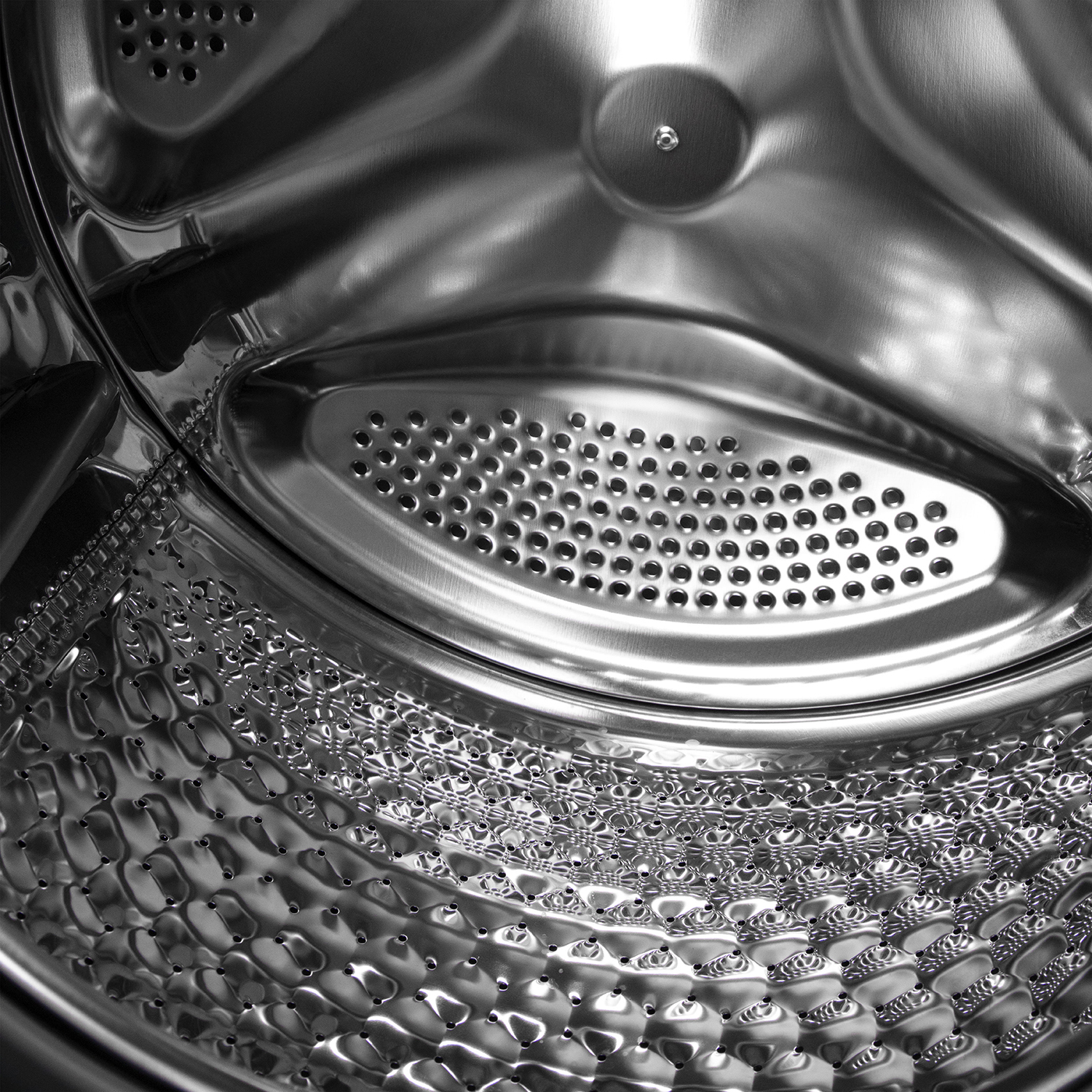 Interno di un cestello di lavatrice, in metallo lucido. Sono visibili sezioni perforate e superfici lisce.
