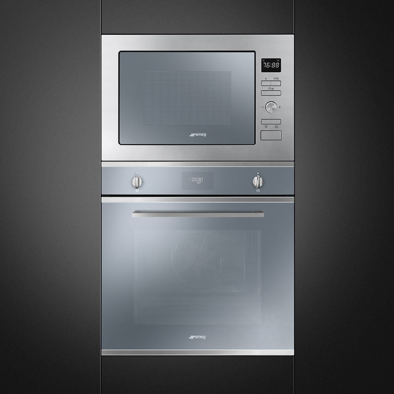 Un horno microondas y un horno integrados, ambos plateados, están empotrados en una pared gris oscura. El microondas muestra la hora.