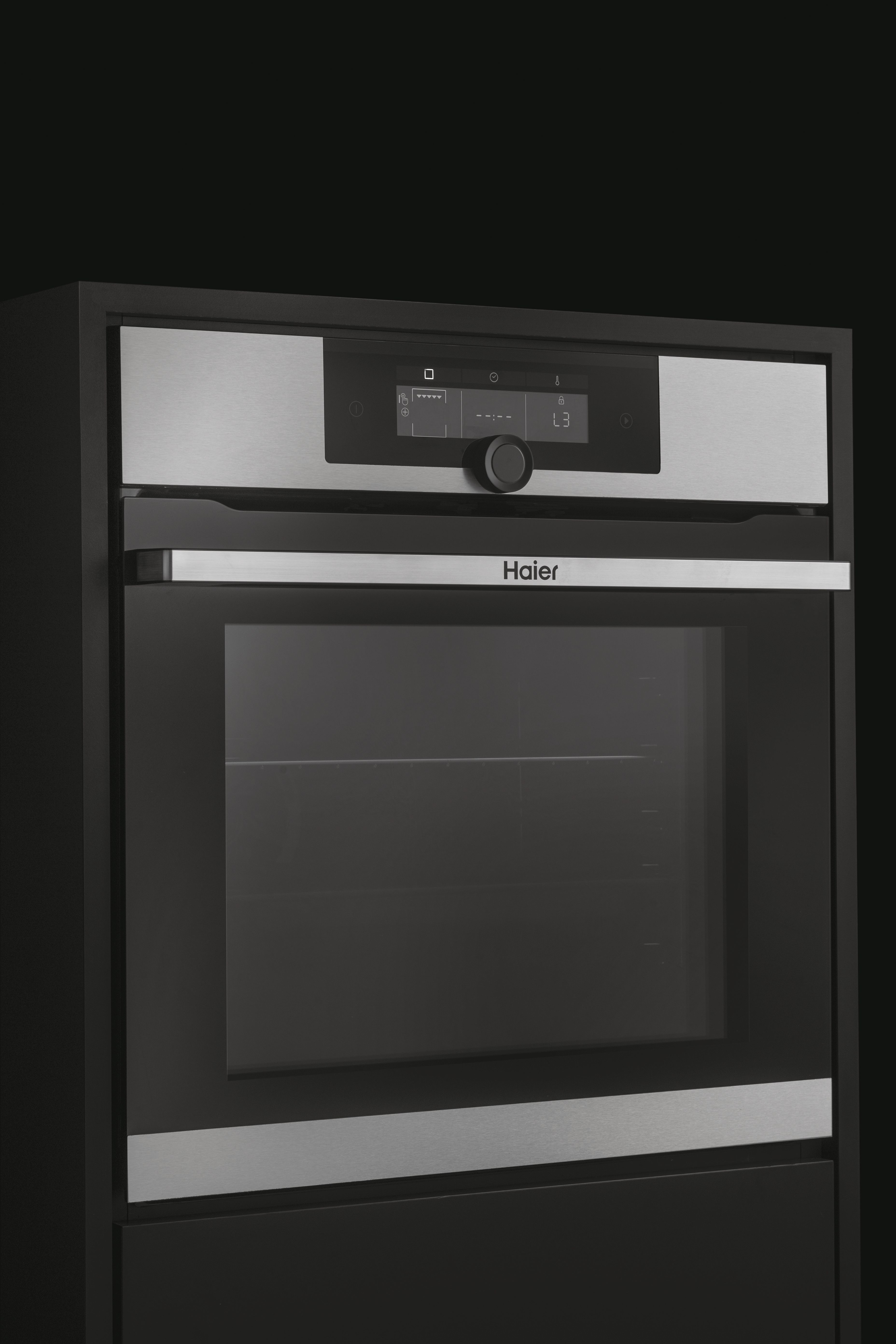 Un forno Haier moderno con pannello in acciaio inossidabile e porta a vetro nera. Dispone di comandi digitali e una manopola.