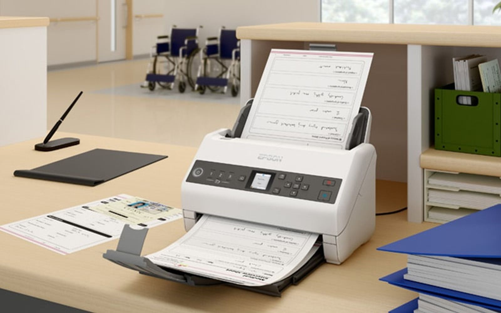 Biały skaner Epson na biurku, skanujący dokumenty. W tle są dokumenty, długopis i wózki inwalidzkie.