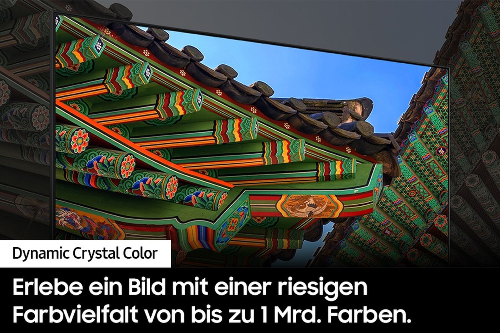 Kolorowy dach budynku ze skomplikowanymi wzorami, zielonymi panelami i pomarańczowymi belkami na tle niebieskiego nieba.