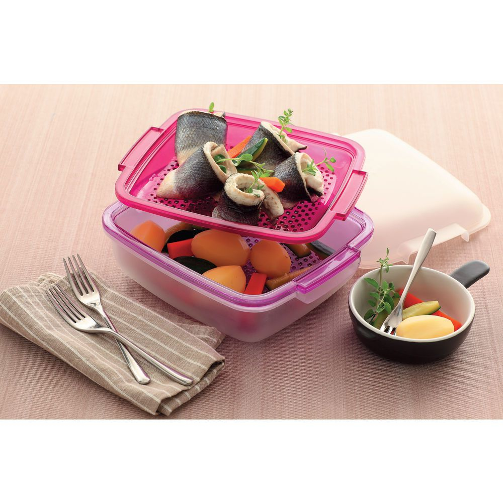 Una vaporiera con involtini di pesce e verdure, accanto a una ciotolina con verdure e una forchetta, e un tovagliolo con forchette.
